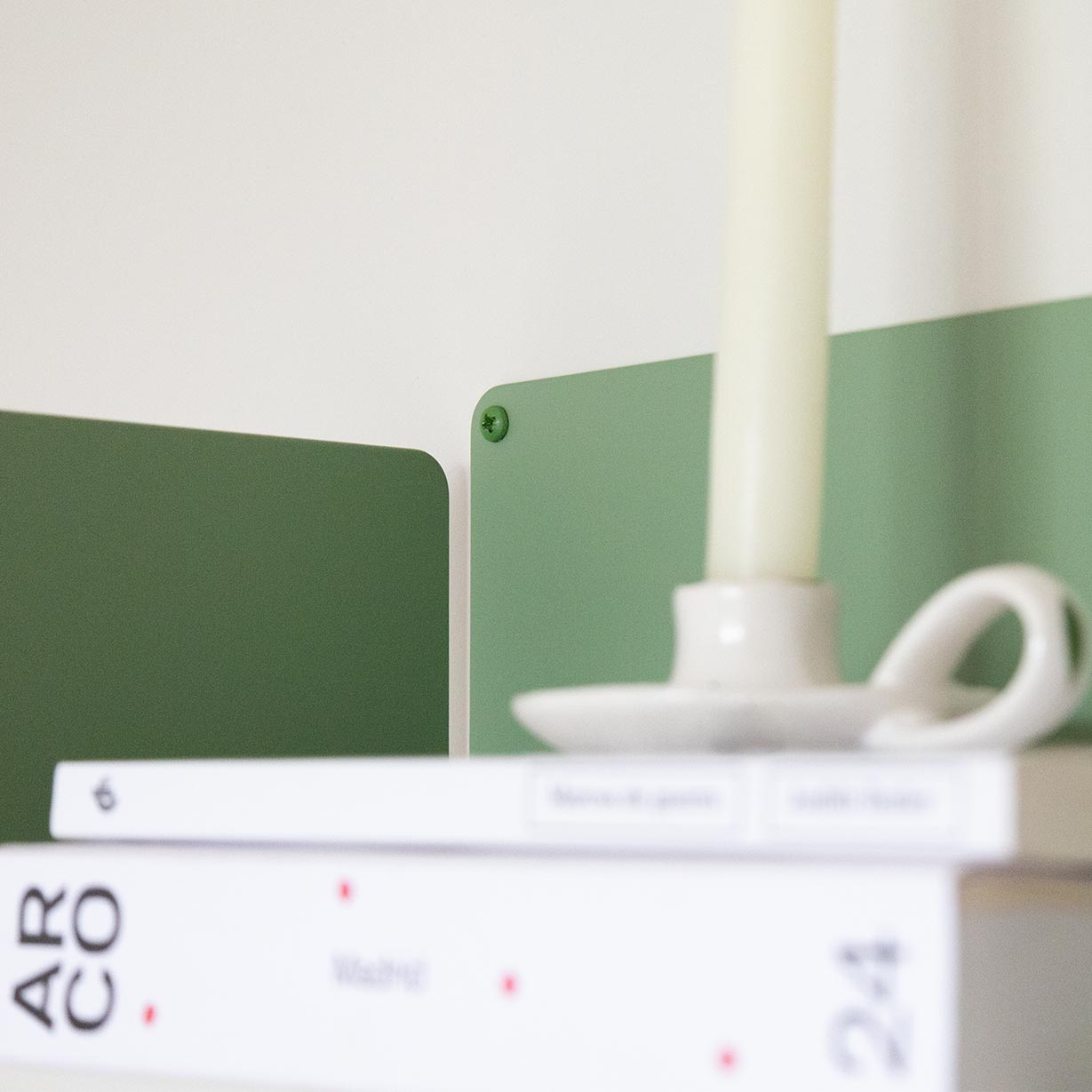 Estante verde de metal colgado en la pared con libros y vela, estilo dopamine decor y moderno