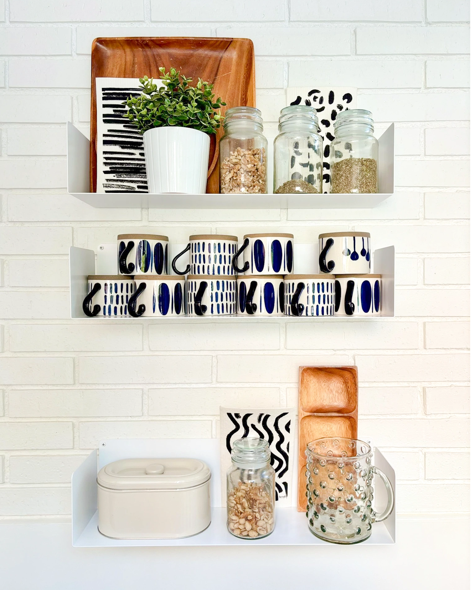 Estantes flotantes blancos en pared cocina con tazas y tarros