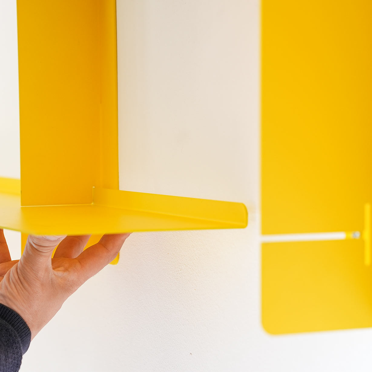 Detalle estantería modular SAMBA amarilla, baldas ajustables acero, sistema flotante pared